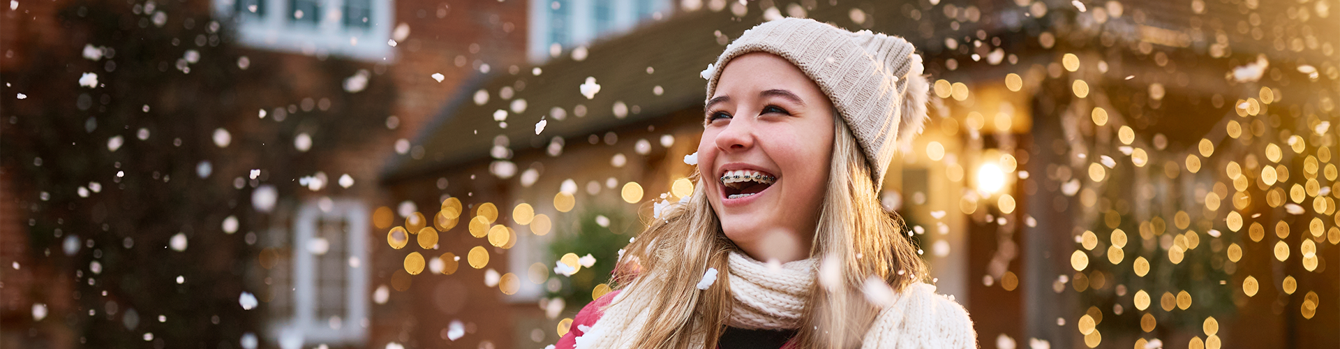 Girl wearing braces carrying presents in the snow.